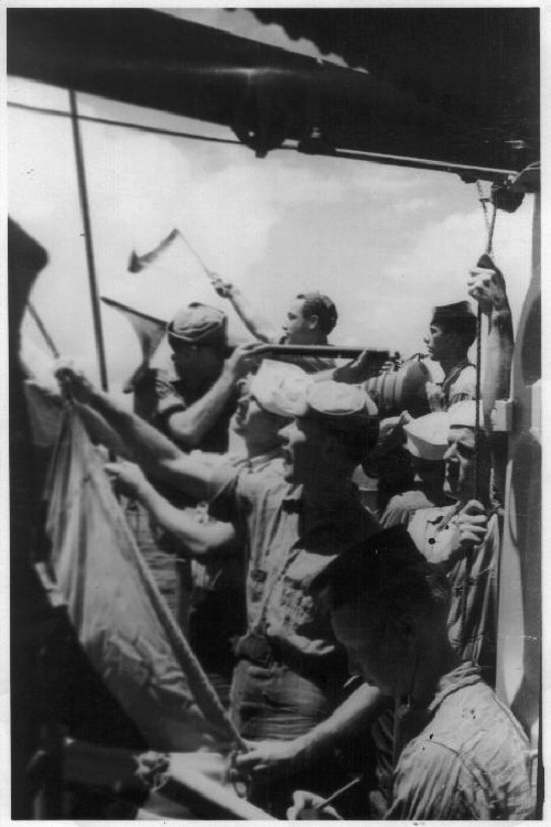 Crew on the bridge.<br>Note use of semaphore flags in background and signal flag being hoisted in the foreground.