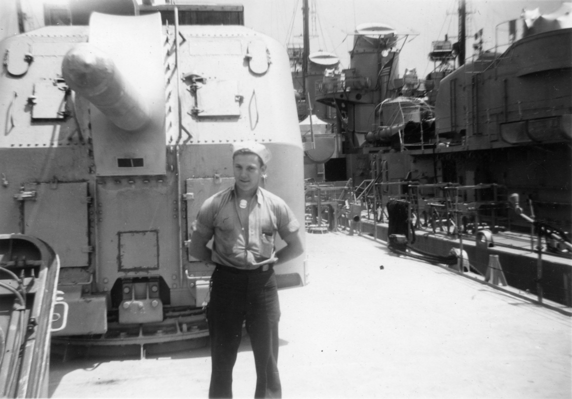 [unknown]<br>Standing in front of a capped 5” gun.<br>Note that the stacks of the adjacent destroyer are also capped.