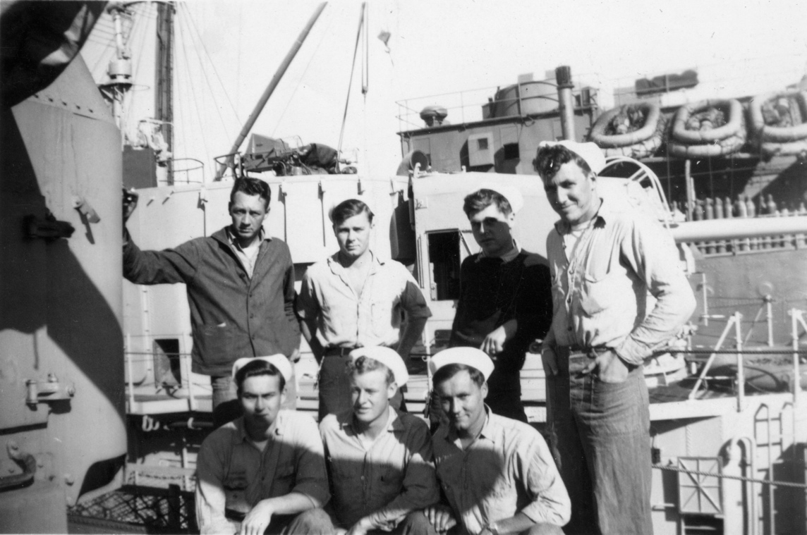 Unknown group photo.<br>Adjacent ship may be a destroyer tender.<br>Note gas cylinders stacked on its deck.
